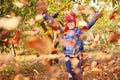 Defocus autumn people. Teen girl raising hand and throwing leaves. Many flying orange, yellow, green dry leaves. Joy Royalty Free Stock Photo