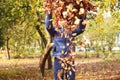 Defocus autumn people. Teen girl raising hand and throwing leaves. Many flying orange, yellow, green dry leaves. Joy Royalty Free Stock Photo