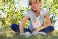 Defocus blonde little emotion girl playing and caress cat, black and white small kitten. Nature blurred green summer background.