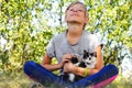 Defocus blonde little girl caress cat, black and white small kitten. Nature green summer background. Girl holding and