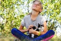 Defocus blonde little girl holding and caress cat, black and white small kitten. Nature green summer background. Girl