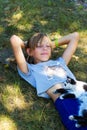 Defocus blonde little girl lying on grass with cat, black and white small cute kitten. Nature green summer background