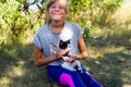 Defocus blonde little smiling girl holding with cat, black and white small cute kitten. Nature blurred green summer Royalty Free Stock Photo