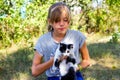 Defocus blonde little smiling girl playing with cat, black and white small kitten. Nature blurred green summer Royalty Free Stock Photo