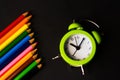 Defocus Close-Up Of light green Alarm Clock With Colored Pencils black Background. time to draw. Art school. Out of