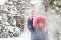 Defocus close-up little funny girl in red warm hat shakes the snow from a branch outside on nature winter snowy forest Royalty Free Stock Photo
