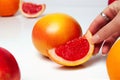 Defocus female hand holding piece of a red grapefruit on white background. Healthy food concept. Fresh orange juice Royalty Free Stock Photo