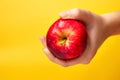 Defocus female hand holding red apple on yellow background. Organic fruit and vegetables. Farmers hands with freshly Royalty Free Stock Photo