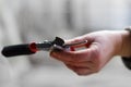 Defocus gardening scissors. Close-up red pruning shears on blurry light background. Hand holding pruning shears or