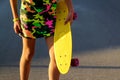 Defocus girl holding yellow penny board. Front view. Summer bright colors. Child hands holding short cruiser pennyboard