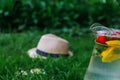 Defocus glass jug of lemonade with strawberry, slice lemon and leaves of mint in on blurred grass background. Pitcher of Royalty Free Stock Photo