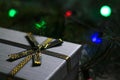 Defocus gray gift with close-up gold bow ribbon on pine or fir tree blurred background with glowing festive green, red Royalty Free Stock Photo