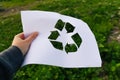 Defocus hand holding cut paper with the logo of green grass nature trash background. Recycling concept. Blurred