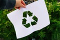 Defocus hand holding cut paper with the logo of recycling on dump garbage trash background. Recycling concept. Pollution