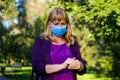 Defocus hands of female in medical mask cleaning her hands with sanitizer outdoor in the park to prevent virus diseases