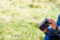 Defocus male hands holding retro photo camera on light green nature background. Copy space. Film grain effect. Man in Royalty Free Stock Photo