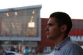 Defocus man face profile. 20s man standing near shopping mall. Night summer. Portrait of young man. Copy space. Out of Royalty Free Stock Photo