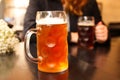 Defocus mug of light beer. Closeup of two hands clinking beer stein glasses. Two friends drinking beer in pub. Out of Royalty Free Stock Photo