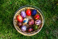 Defocus multicolored easter eggs. Decorated pysanka and krashanka. Wooden Basket With Easter Eggs In The Green Grass