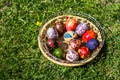 Defocus multicolored easter eggs. Decorated pysanka and krashanka. Wooden Basket With Easter Eggs In The Green Grass