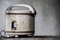 Defocus of old white electric rice cooker Was set on the edge of the cement wall, Old electric rice cooker rusty and has expired Royalty Free Stock Photo