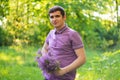 Defocus pleasant cheerful handsome young guy looking aside and holding bouquet of lilac flowers while feeling happy Royalty Free Stock Photo