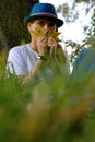 Defocus portrait of a funny young woman with brown hair wearing a hat outdoors. Female hand holding yellow dry leaves Royalty Free Stock Photo