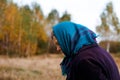 Defocus portrait of russian grandmother senior old woman standing in yellow autumn park. Old women in coat and shawl