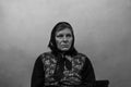 Defocus portrait of 60s russian grandmother senior old woman seating indoors. Old women shawl. Sad person. White dirty