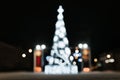 Defocus shining decorated large Christmas tree ona city square on winter night, outdoors. Royalty Free Stock Photo