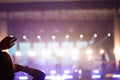 Defocus silhouette of one woman raise hand up in music concert with purple and white color spotlight on stage background
