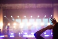 Defocus silhouette of one woman raise hand up in music concert with purple and white color spotlight on stage background