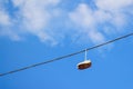 Defocus sneakers hanging from electrical wire against a blue sky background. The concept of urban culture, sale of Royalty Free Stock Photo