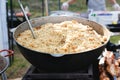 Defocus stirring the pilaf in a large bowl during cooking outdoors. National dish. Cooking of traditional pilaf in big