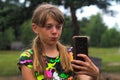 Defocus surprised ten year old girl find something on smart phone. Beautiful teenage girl takes selfie while standing Royalty Free Stock Photo