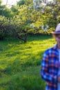 Defocus tranquility vertical photo. Blurred woman in checkered shirt and hat on foreground. Surrealism and metaphor