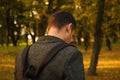 Defocus young man holding phone. Man using smart phone in autumn park. Typing text message or reading social media at Royalty Free Stock Photo