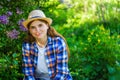 Defocus young summer woman. Beautiful woman in checkered shirt and hat with lilac bunch and meadow of flowers in spring