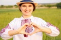 Defocus young ukrainian woman portrait. Meadow nature background. Showing sign love Ukraine. Smiling ukrainian girl