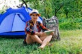 Defocus young woman working on tablet near camping tent outdoors surrounded by beautiful nature. Freelance, sabbatical