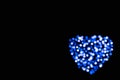 Defocused blue and white circles of light in the shape of a heart with bokeh effect on a black background with copy space Royalty Free Stock Photo