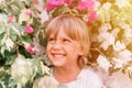 Defocused blurred portrait of face candid little happy smiling five year old blonde kid boy with green eyes in pink and white flow
