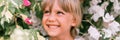 Defocused blurred portrait of face candid little happy smiling five year old blonde kid boy with green eyes in pink and white flow