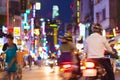 Ho Chi Minh City: defocused colorful scene of the night street perspective with blurred motorcycles, passersby, sign boards