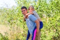 Defocused brother giving sister ride on back in forest. Portrait of happy girl on young man shoulders, piggyback. Family