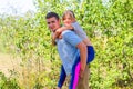 Defocused brother giving sister ride on back in park. Portrait of happy girl on young man shoulders, piggyback. Family playing