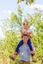 Defocused brother giving sister ride on back. Portrait of happy girl on man shoulders, piggyback. Family playing outside. Summer