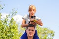 Defocused brother giving sister ride on back. Portrait of happy girl on man shoulders, piggyback. Girl holding cat Royalty Free Stock Photo