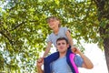 Defocused brother riding sister on back. Portrait of happy girl on man shoulders, piggyback. Girl fly, raise hand