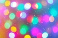 Defocused colorful ligths of Christmas tree. Multicolored bokeh lights during a snowfall. Background for greeting card.